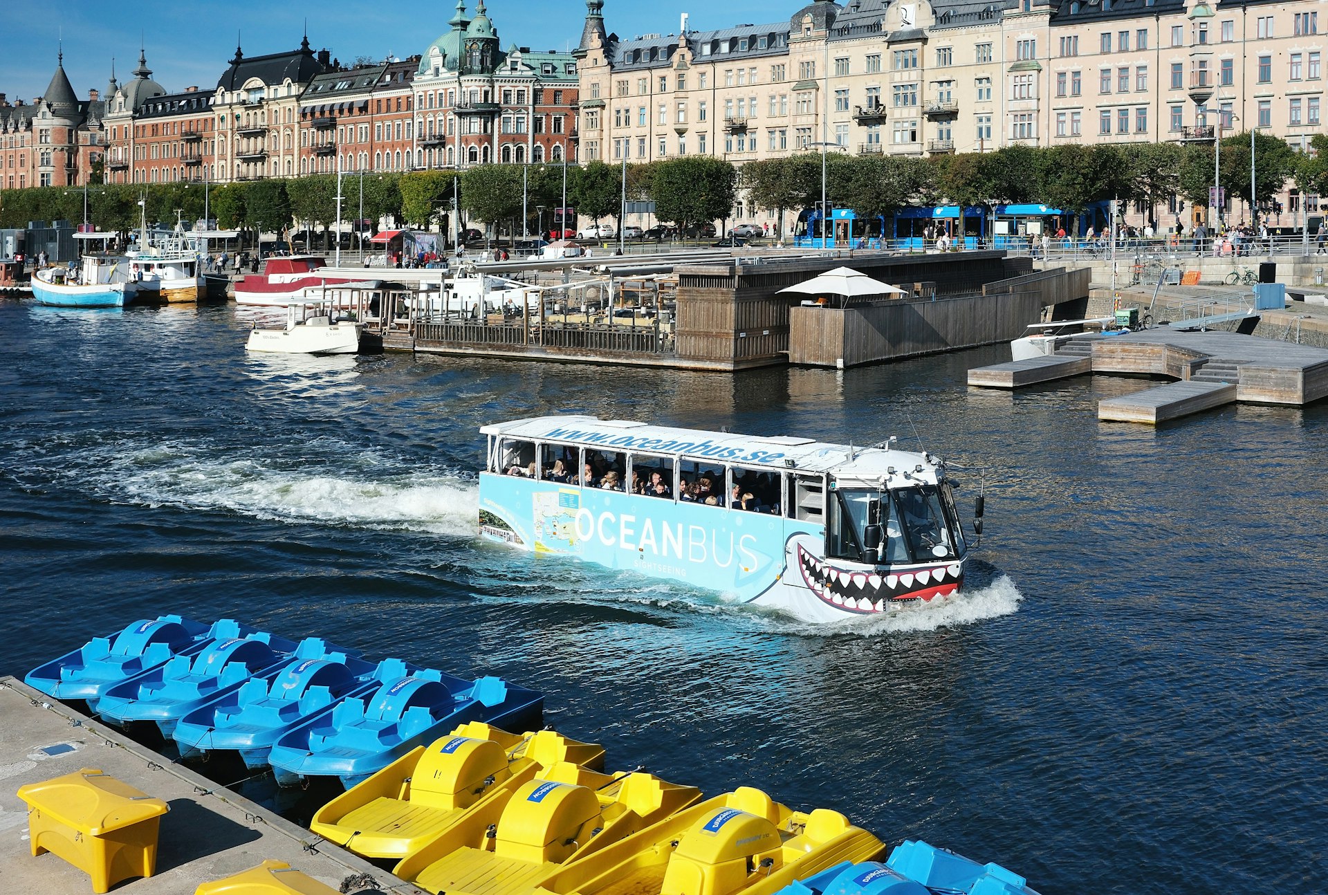A boat traveling down a river next to tall buildings